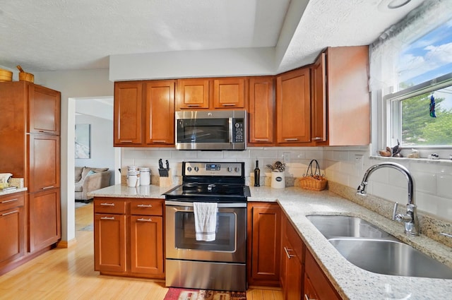 5508 Aspen Rd, Columbus, OH 43229 - kitchen with appliances with stainless steel finishes, a sink, light wood-style floors, light stone counters, and a textured ceiling