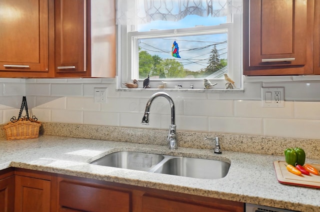 5508 Aspen Rd, Columbus, OH 43229 - kitchen featuring a sink, brown cabinets, decorative backsplash, light stone counters, and dishwasher