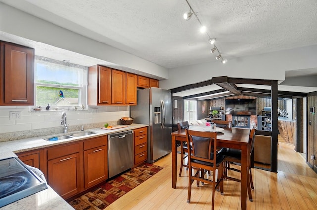 5508 Aspen Rd, Columbus, OH 43229 - kitchen with stainless steel appliances, a sink, light wood-type flooring, brown cabinetry, and a textured ceiling