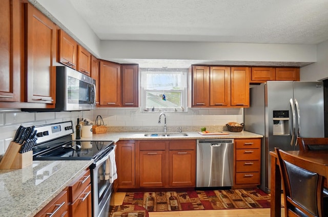 5508 Aspen Rd, Columbus, OH 43229 - kitchen featuring appliances with stainless steel finishes, a sink, backsplash, a textured ceiling, and light stone counters