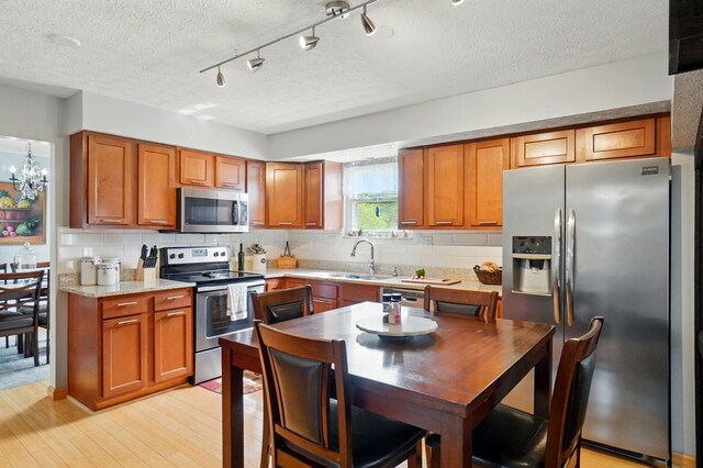 5508 Aspen Rd, Columbus, OH 43229 - kitchen featuring stainless steel appliances, a sink, brown cabinetry, and a textured ceiling