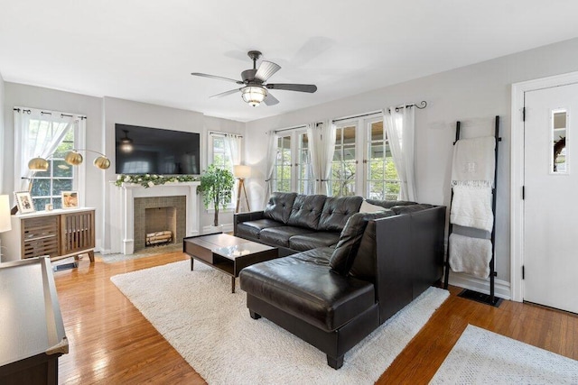 living room featuring ceiling fan, healthy amount of natural light, a fireplace with flush hearth, and wood finished floors