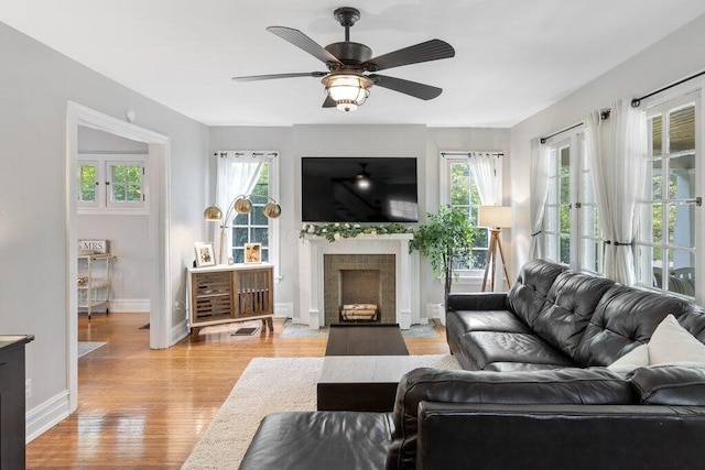 living room with healthy amount of natural light, baseboards, ceiling fan, and light wood-type flooring