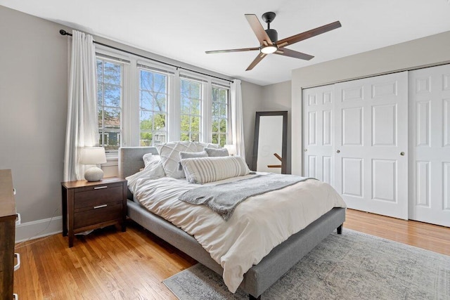 bedroom with light wood-style flooring, a closet, baseboards, and ceiling fan
