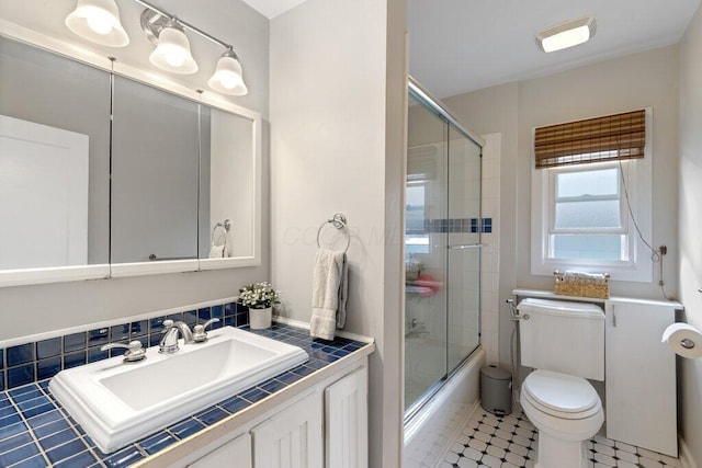 bathroom featuring toilet, bath / shower combo with glass door, and vanity