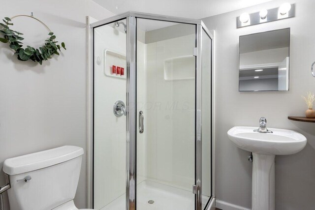 full bath featuring a stall shower, toilet, and a sink