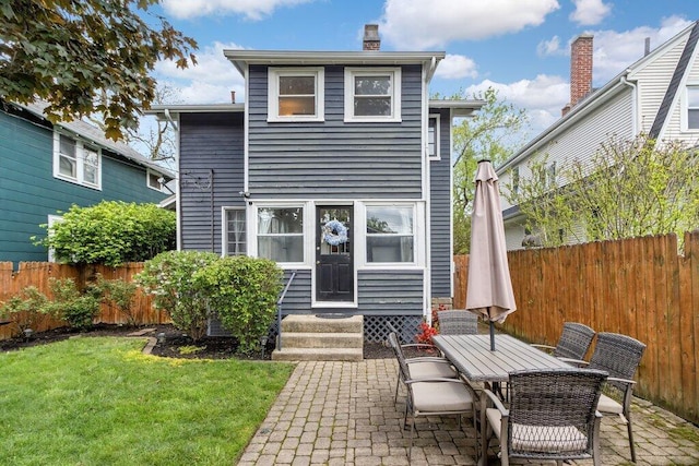 back of house with entry steps, a patio, a chimney, and outdoor dining space
