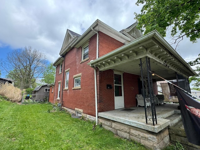 rear view of house with a lawn and brick siding