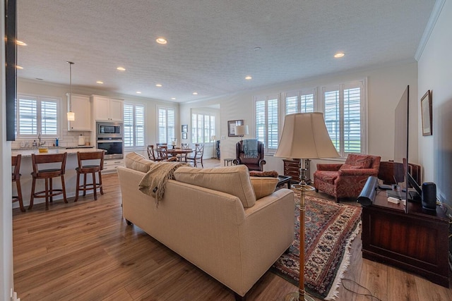 6210 Callaway Sq W, New Albany, OH 43054 - living area featuring healthy amount of natural light, crown molding, recessed lighting, a textured ceiling, and light wood-style floors