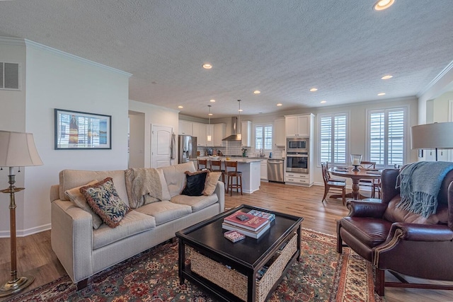 6210 Callaway Sq W, New Albany, OH 43054 - living room with light wood finished floors, recessed lighting, a textured ceiling, crown molding, and baseboards