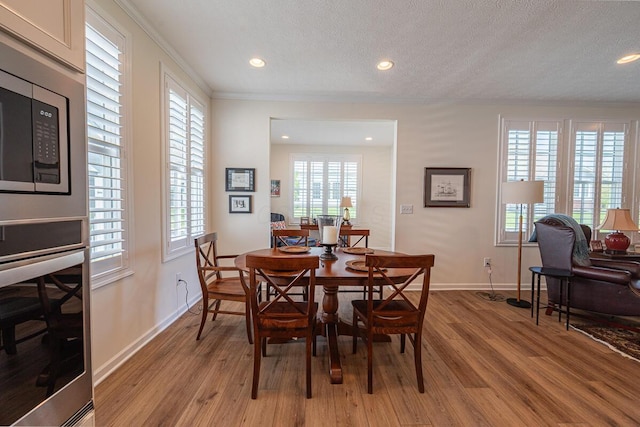6210 Callaway Sq W, New Albany, OH 43054 - dining room featuring crown molding, light wood-type flooring, a textured ceiling, recessed lighting, and baseboards