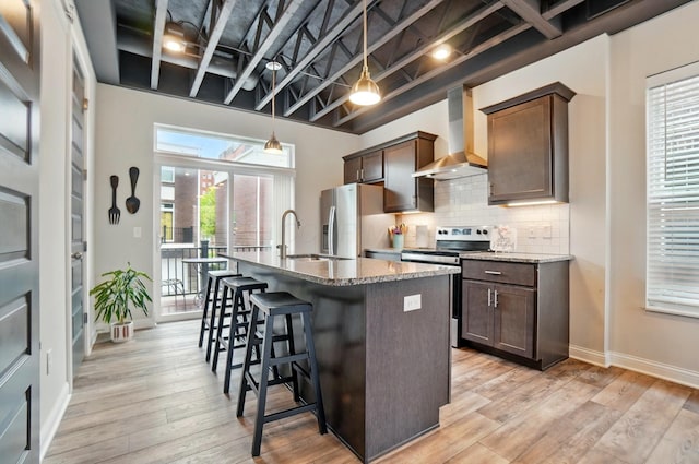20 N Center St Unit 20, Springfield, OH 45502 - kitchen featuring wall chimney exhaust hood, stainless steel appliances, a sink, a center island with sink, and a breakfast bar