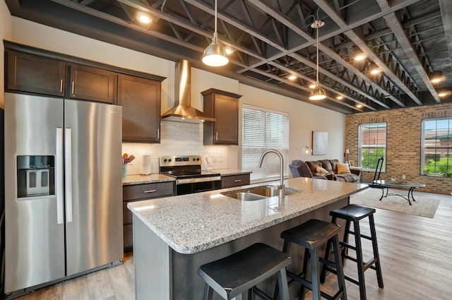 20 N Center St Unit 20, Springfield, OH 45502 - kitchen with stainless steel appliances, wall chimney exhaust hood, a sink, light stone counters, and light wood-style floors