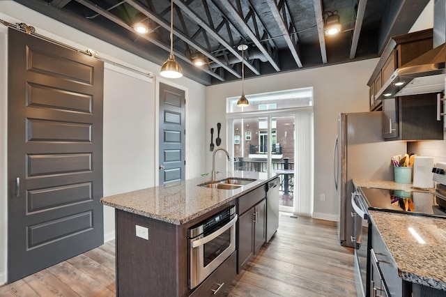 20 N Center St Unit 20, Springfield, OH 45502 - kitchen with appliances with stainless steel finishes, a sink, wall chimney range hood, a kitchen island with sink, and decorative light fixtures