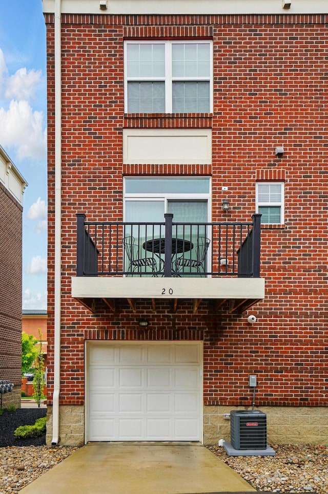 20 N Center St Unit 20, Springfield, OH 45502 - view of front facade with a balcony, an attached garage, brick siding, driveway, and central AC unit