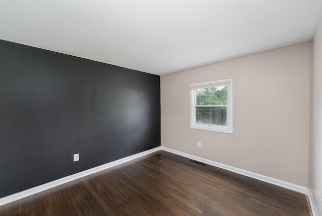 spare room featuring baseboards and wood finished floors