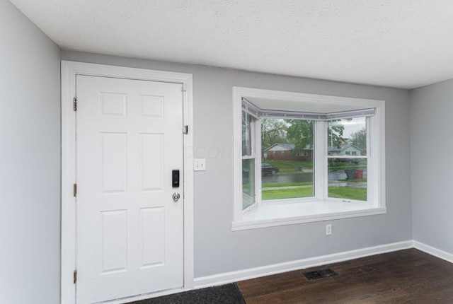 foyer featuring dark wood-type flooring, baseboards, and a textured ceiling