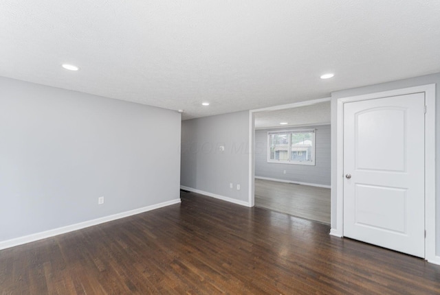 spare room with baseboards, dark wood-style flooring, and recessed lighting