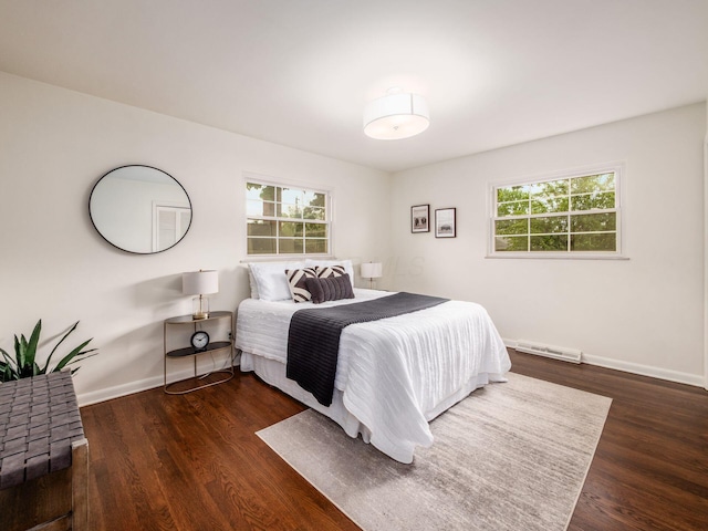 bedroom with multiple windows, wood finished floors, and baseboards