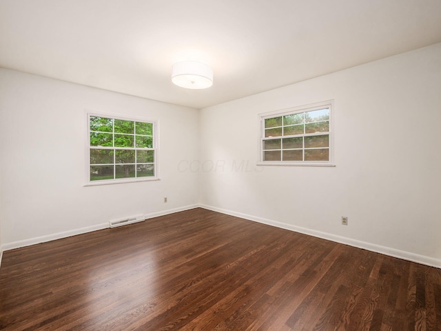 unfurnished room featuring dark wood-type flooring and baseboards