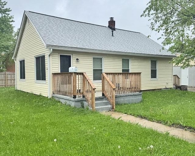 back of house with a deck, a chimney, a lawn, and a shingled roof