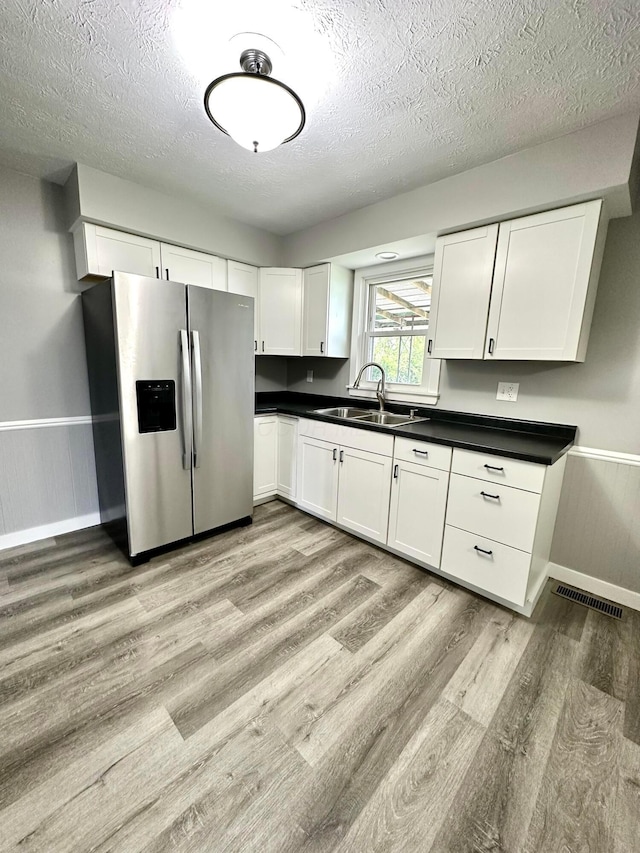 375 N Main St, Marion, OH 43302 - kitchen featuring stainless steel refrigerator with ice dispenser, a sink, light wood-type flooring, dark countertops, and a textured ceiling