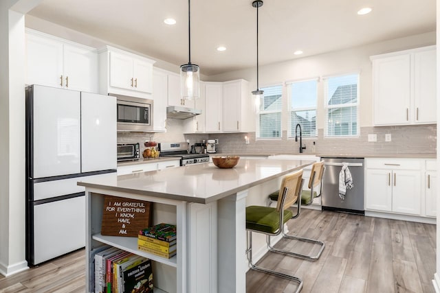 kitchen featuring stainless steel appliances, open shelves, white cabinetry, a sink, and light wood-style floors
