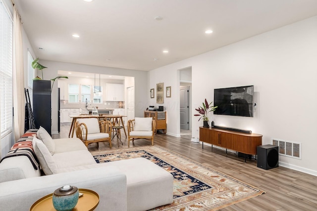 living area featuring light wood-type flooring, recessed lighting, and baseboards