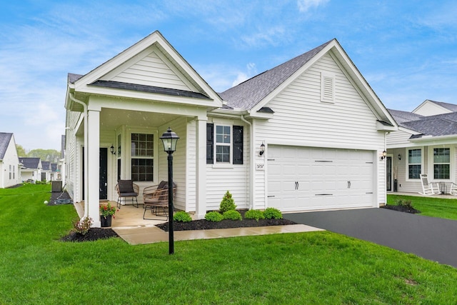 view of front of property featuring a porch, a front lawn, driveway, an attached garage, and a shingled roof