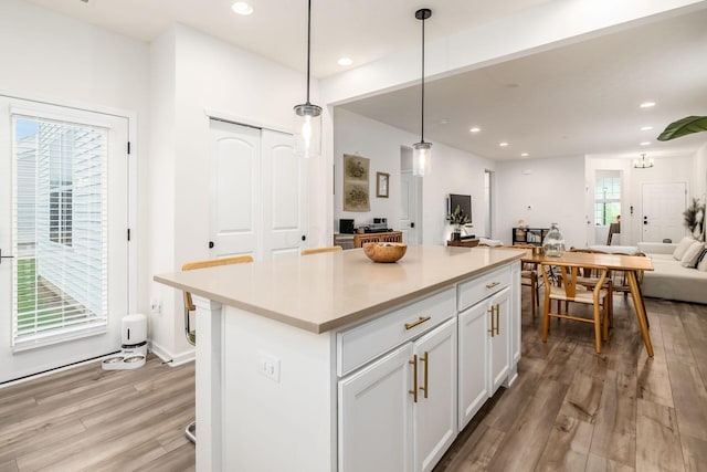 kitchen featuring open floor plan, light wood-style floors, a kitchen island, recessed lighting, and light countertops