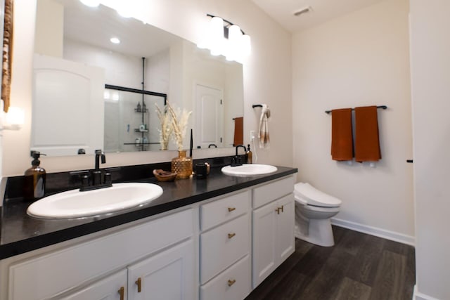 full bath with wood finished floors, a stall shower, toilet, double vanity, and baseboards