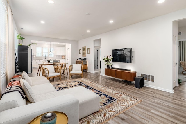 living area featuring recessed lighting, light wood-type flooring, and baseboards