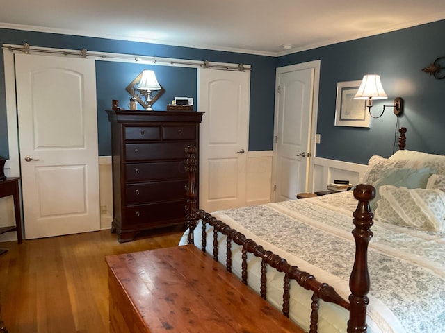 1893 Lovers Ln, New Lexington, OH 43764 - bedroom featuring a barn door, wood finished floors, wainscoting, ornamental molding, and a decorative wall