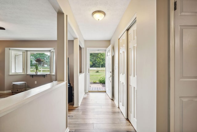 10842 Johnstown Rd, New Albany, OH 43054 - doorway featuring a textured ceiling, light wood-type flooring, and baseboards