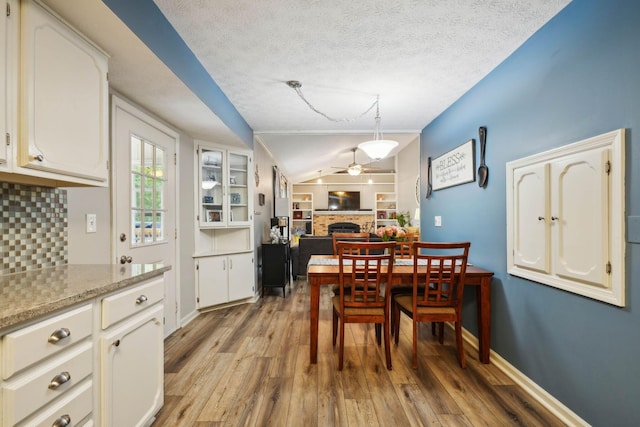 10842 Johnstown Rd, New Albany, OH 43054 - dining space with a ceiling fan, a brick fireplace, light wood-type flooring, lofted ceiling, and a textured ceiling