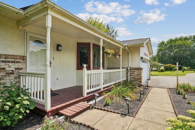 10842 Johnstown Rd, New Albany, OH 43054 - property entrance featuring covered porch, concrete driveway, an attached garage, brick siding, and stucco siding