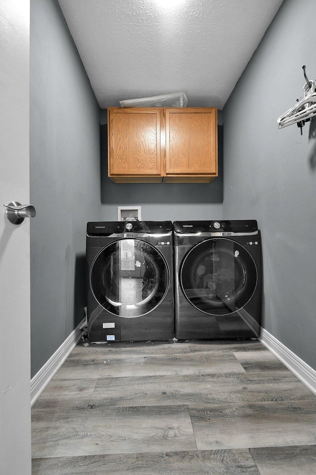 10129 Granden St, Pickerington, OH 43147 - laundry area featuring cabinet space, washing machine and clothes dryer, wood finished floors, baseboards, and a textured ceiling