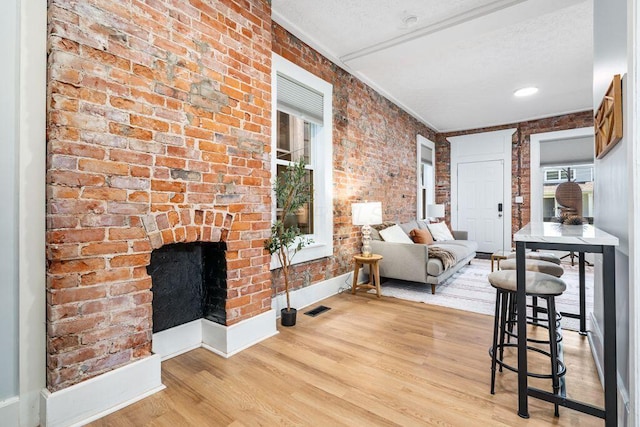 453-455 S 22nd St, Columbus, OH 43205 - living room featuring baseboards, light wood finished floors, brick wall, and a fireplace