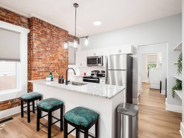 453-455 S 22nd St, Columbus, OH 43205 - kitchen with appliances with stainless steel finishes, a sink, brick wall, light wood-style floors, and white cabinetry