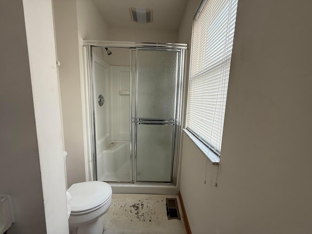 bathroom featuring toilet, a stall shower, and baseboards