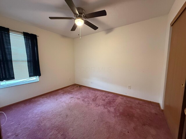 carpeted empty room featuring a ceiling fan and baseboards
