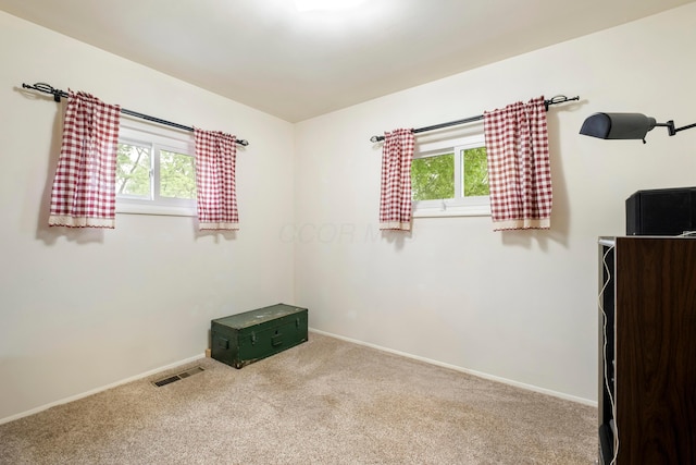 carpeted spare room featuring plenty of natural light and baseboards