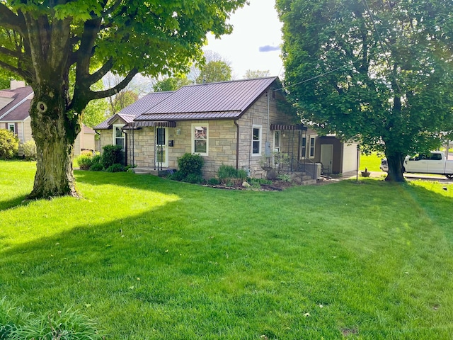 view of front facade featuring stone siding, a standing seam roof, a front yard, and metal roof