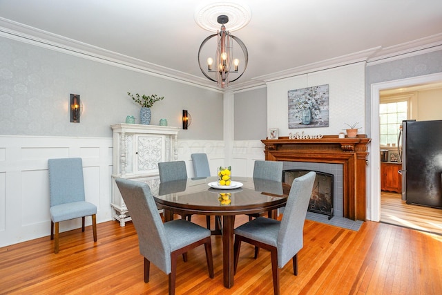 404 Rawling St, Washington Court House, OH 43160 - dining room with light wood-style floors, a chandelier, crown molding, a tile fireplace, and wainscoting