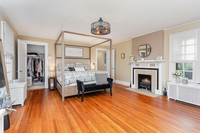 404 Rawling St, Washington Court House, OH 43160 - bedroom featuring radiator heating unit, light wood finished floors, ornamental molding, a walk in closet, and a fireplace with flush hearth
