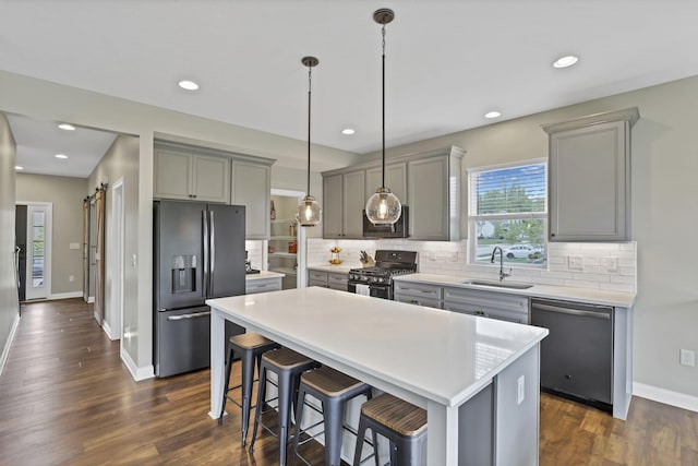 kitchen with stainless steel appliances, gray cabinetry, a sink, baseboards, and light countertops
