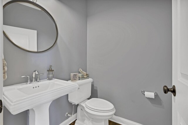 bathroom featuring toilet, a sink, and baseboards