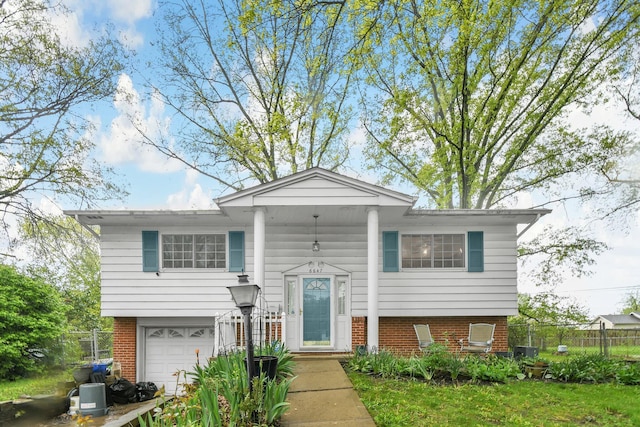 split foyer home with brick siding, fence, an attached garage, and central AC unit