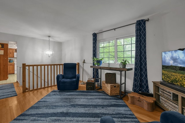 living area with light wood-style floors, an upstairs landing, and a chandelier