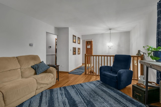 living area featuring wood finished floors, a chandelier, and baseboards